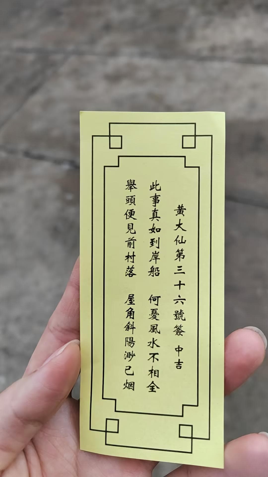 手持黃大仙第三十六號籤實物,籤上印有中吉及此事真如到岸船等四句籤詩